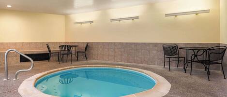 A pool area with a hot tub, seating, and a wall-mounted light fixture.