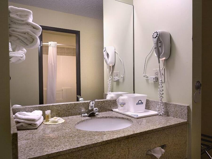 Un baño con encimera de granito, lavamanos, espejo, toallero y secador de pelo.