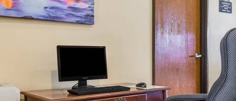 A wooden desk with a computer, a chair, and a painting of a river.