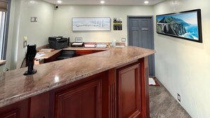 A kitchen with a marble countertop, wooden cabinets, a printer, and a framed picture on the wall. - Inn By the Bay Monterey (Monterey)