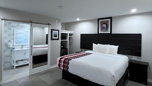 A modern bedroom with a large bed, a black headboard, and a walk-in closet with a sliding door. - Inn By the Bay Monterey (Monterey)