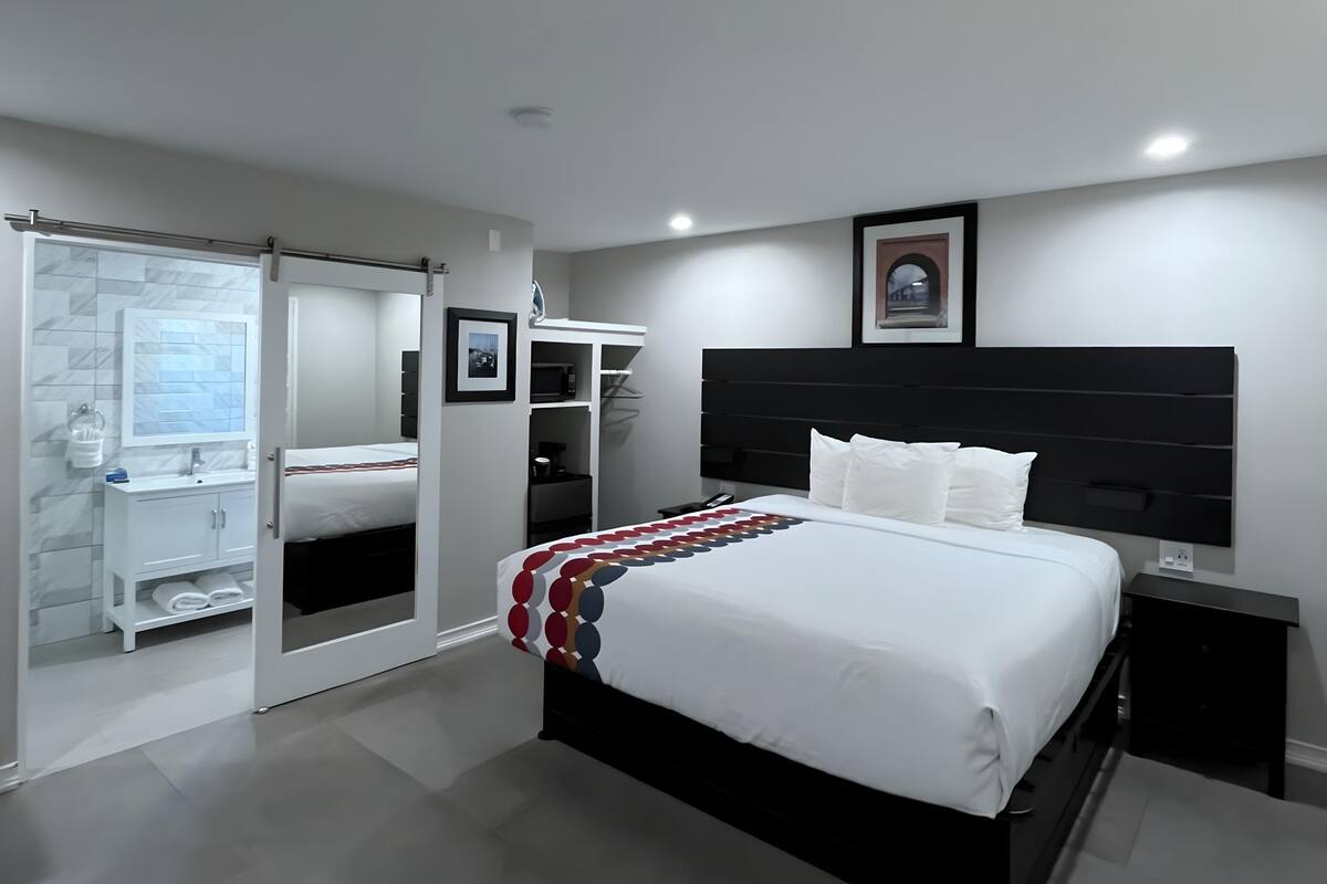 A modern bedroom with a large bed, a black headboard, and a walk-in closet with a sliding door.