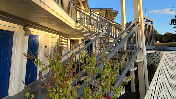 A two-story building with a covered staircase and a balcony. - Inn By the Bay Monterey (Monterey)