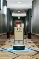 A self-service kiosk in a hotel hallway with a sign reading "Cy At Your Service."