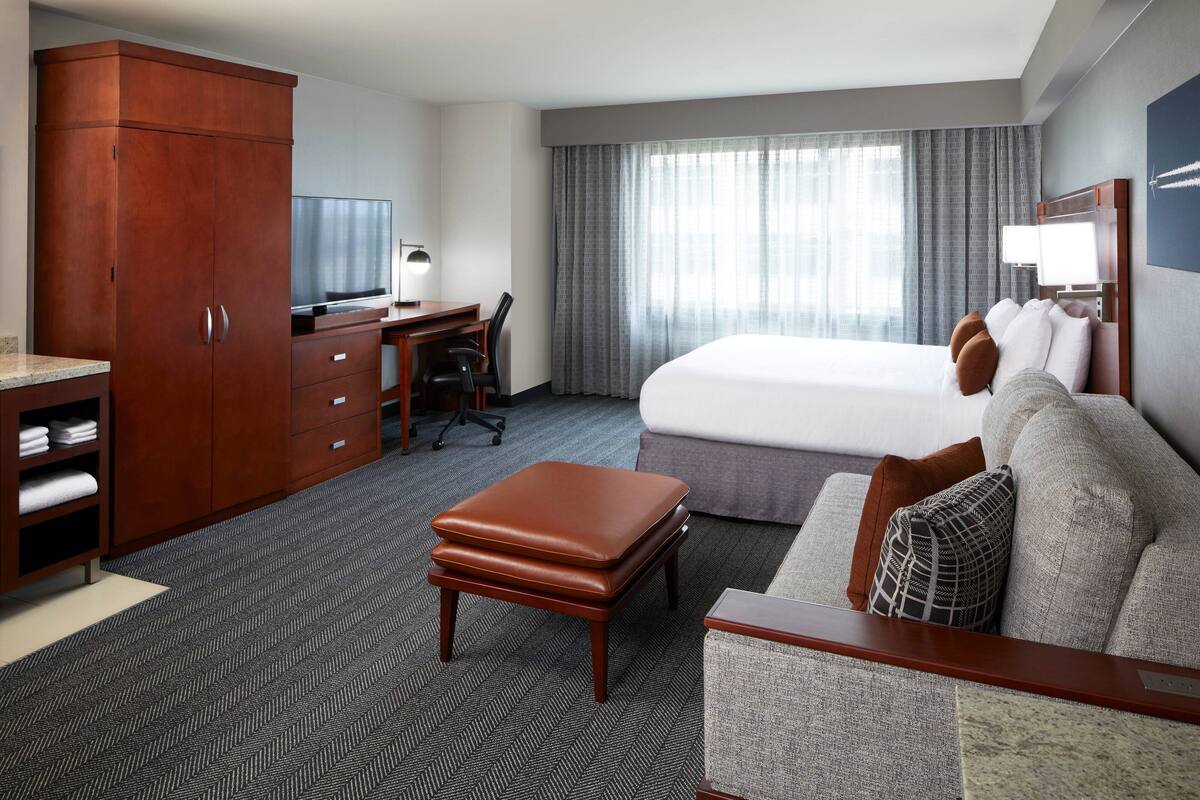 Ein Hotelzimmer mit Bett, Schreibtisch, Fernseher und Kleiderschrank.