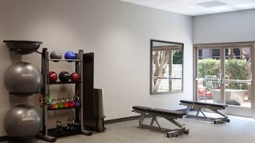 A gym with exercise equipment, a bench, and a window with a view of the outdoors.