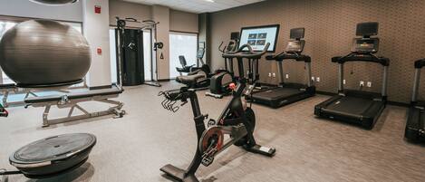 A gym with exercise equipment including a stationary bike, elliptical, and treadmills.