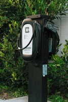 Una estación de carga pública para vehículos eléctricos con un cable conectado a un automóvil.