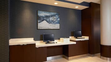 A reception desk with two monitors, a printer, and a framed artwork on the wall.