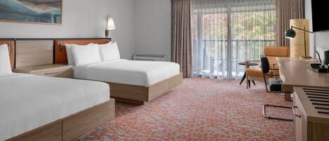 A hotel room with two beds, a desk, a chair, a TV, and a large window with curtains.
