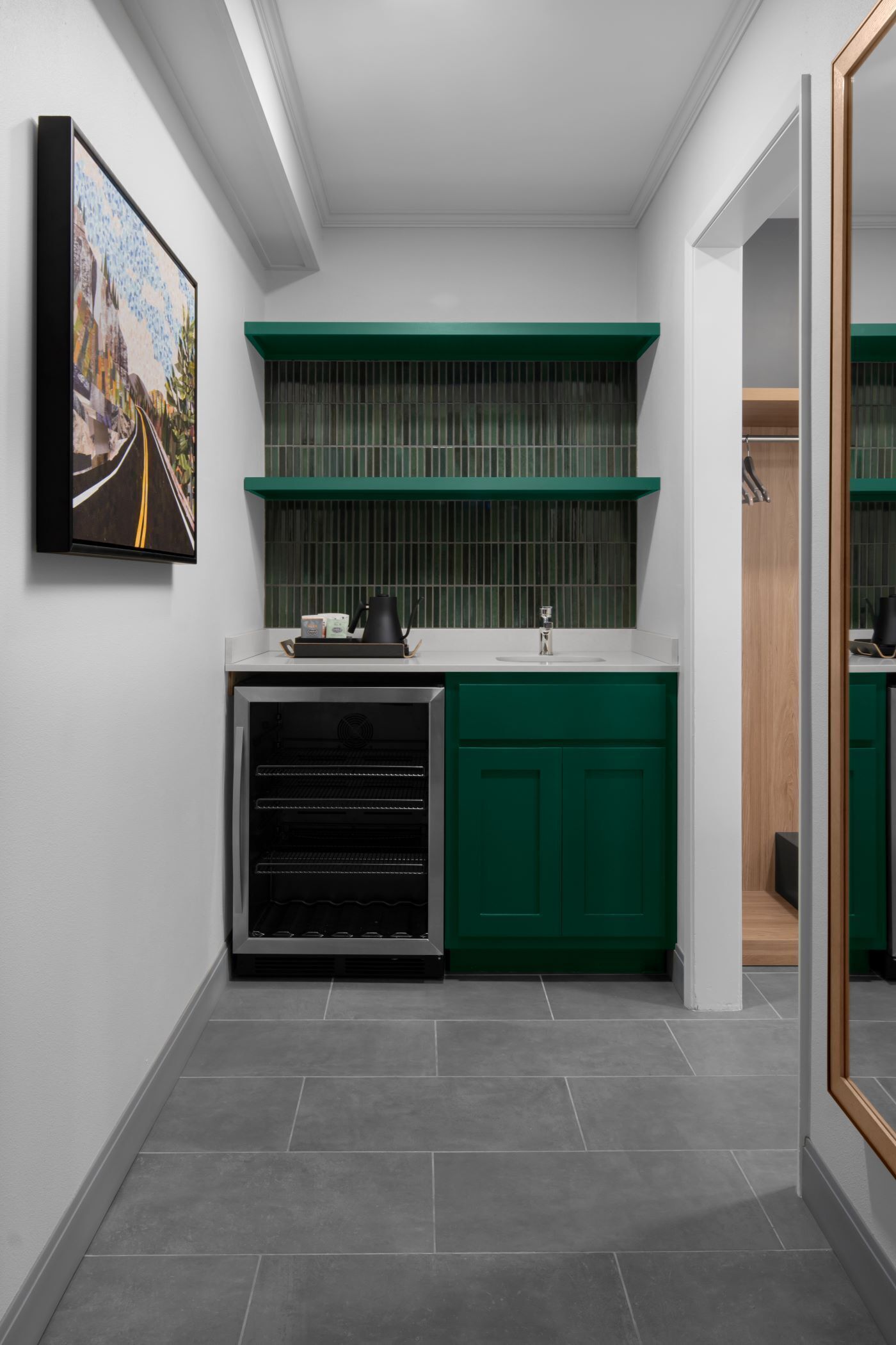 Una cocina compacta con armarios verdes, horno integrado y una pequeña encimera.