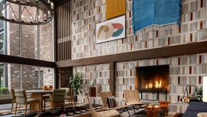 A spacious lounge with a fireplace, modern furniture, and a patterned wall.