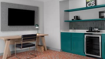 Une cuisine moderne avec des meubles de couleur turquoise, un four encastré et un téléviseur à écran plat fixé au mur.