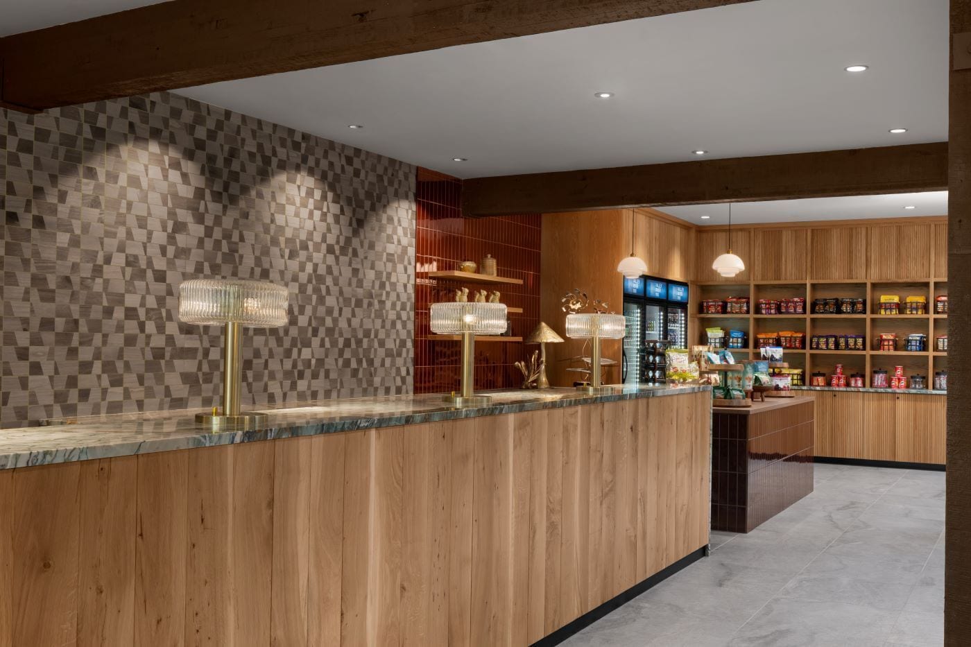 Un área de recepción moderna con un mostrador de madera, pared estampada de cuadros y estanterías con productos.