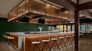 A modern bar area with a central island, bar stools, and a variety of bottles.