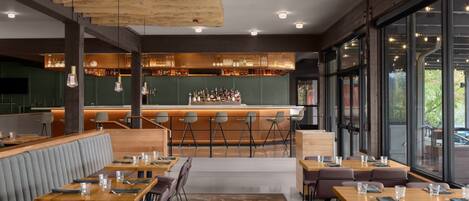 En moderne restaurant med barområde, store vinduer og et træloft.