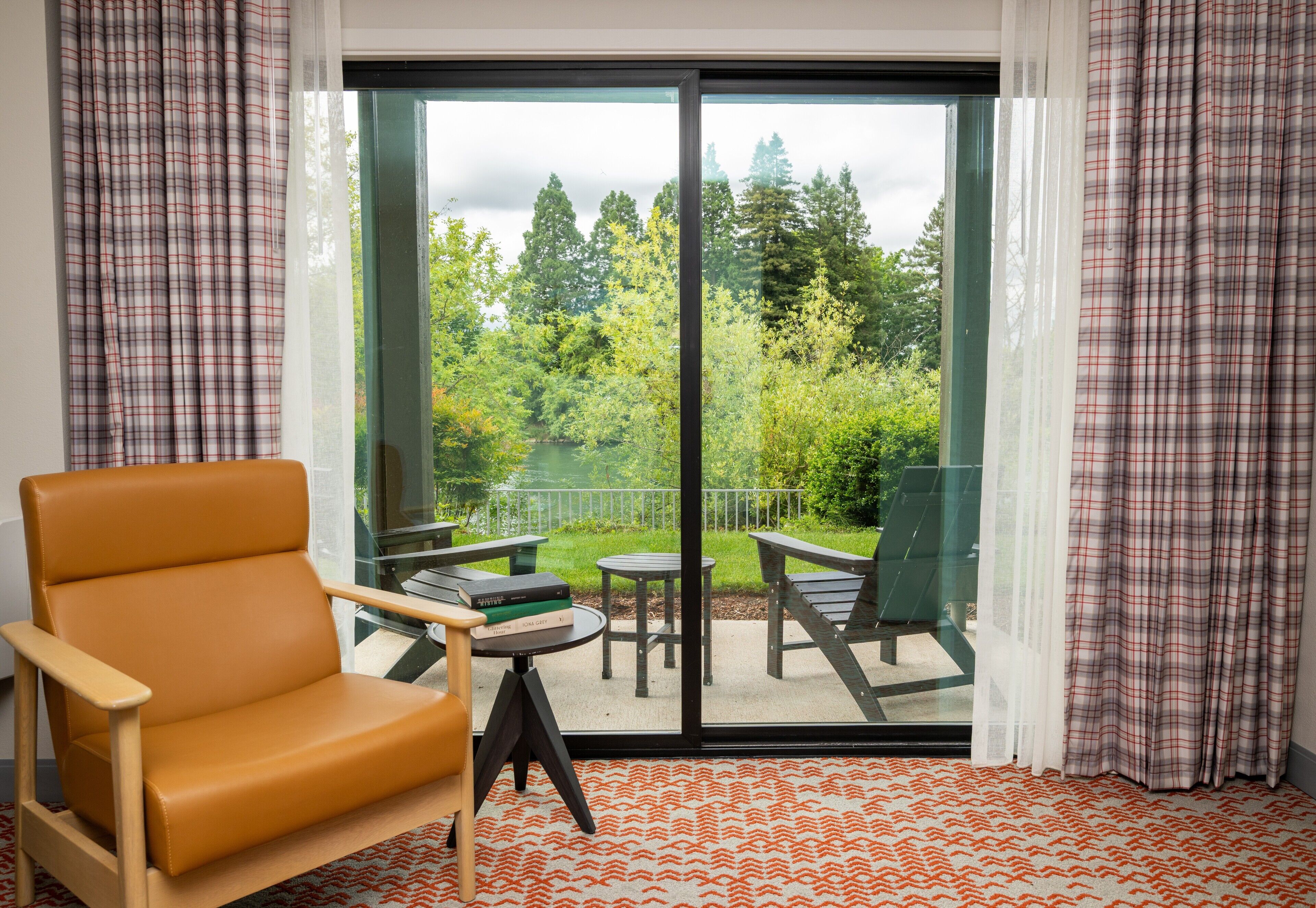 Una habitación con un amplio ventanal corredera que da a un patio exterior con mesa y sillas.