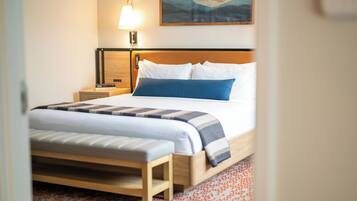A neatly made bed with a wooden headboard, a bedside lamp, and a patterned rug.