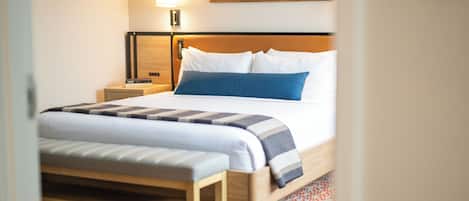 A neatly made bed with a wooden headboard, a bedside lamp, and a patterned rug.