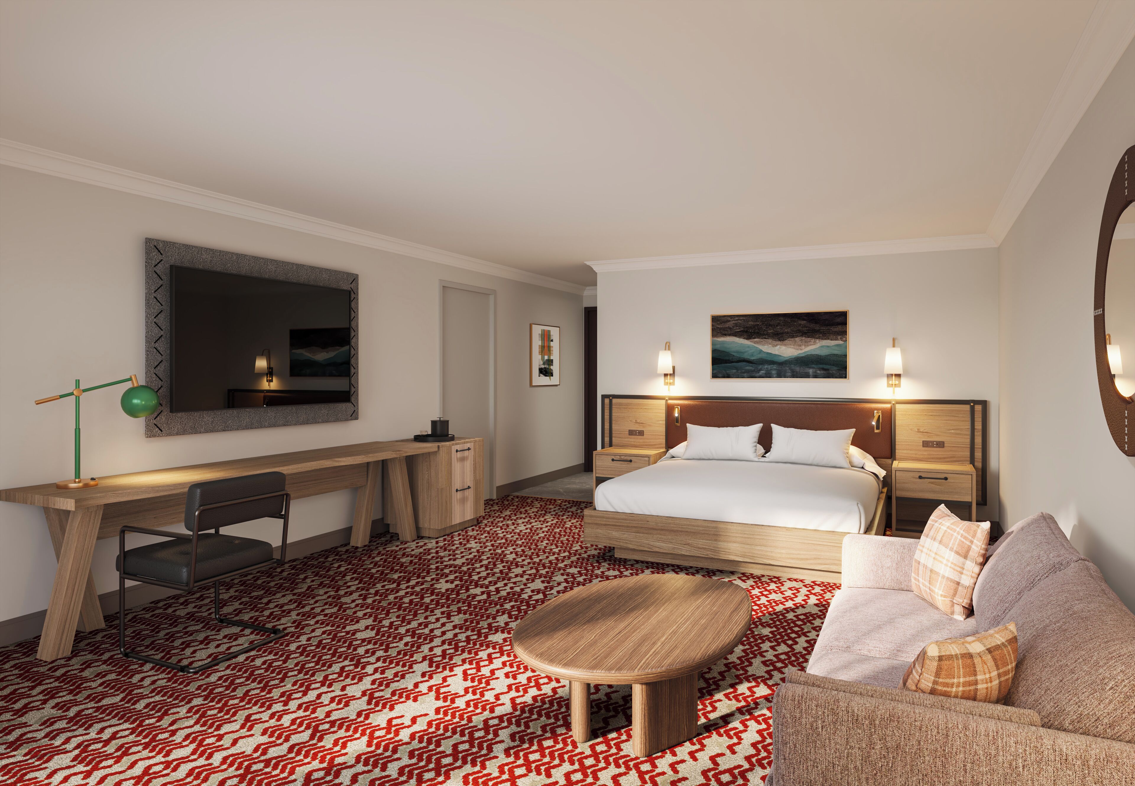 A hotel room with a large bed, a desk, a chair, a sofa, and a small round table.