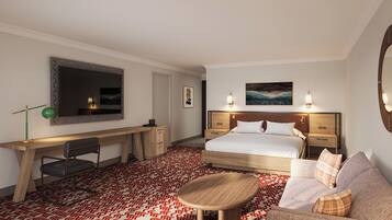 A hotel room with a large bed, a desk, a chair, a sofa, and a small round table.