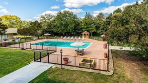 A backyard with a swimming pool, lounge chairs, and a gazebo.