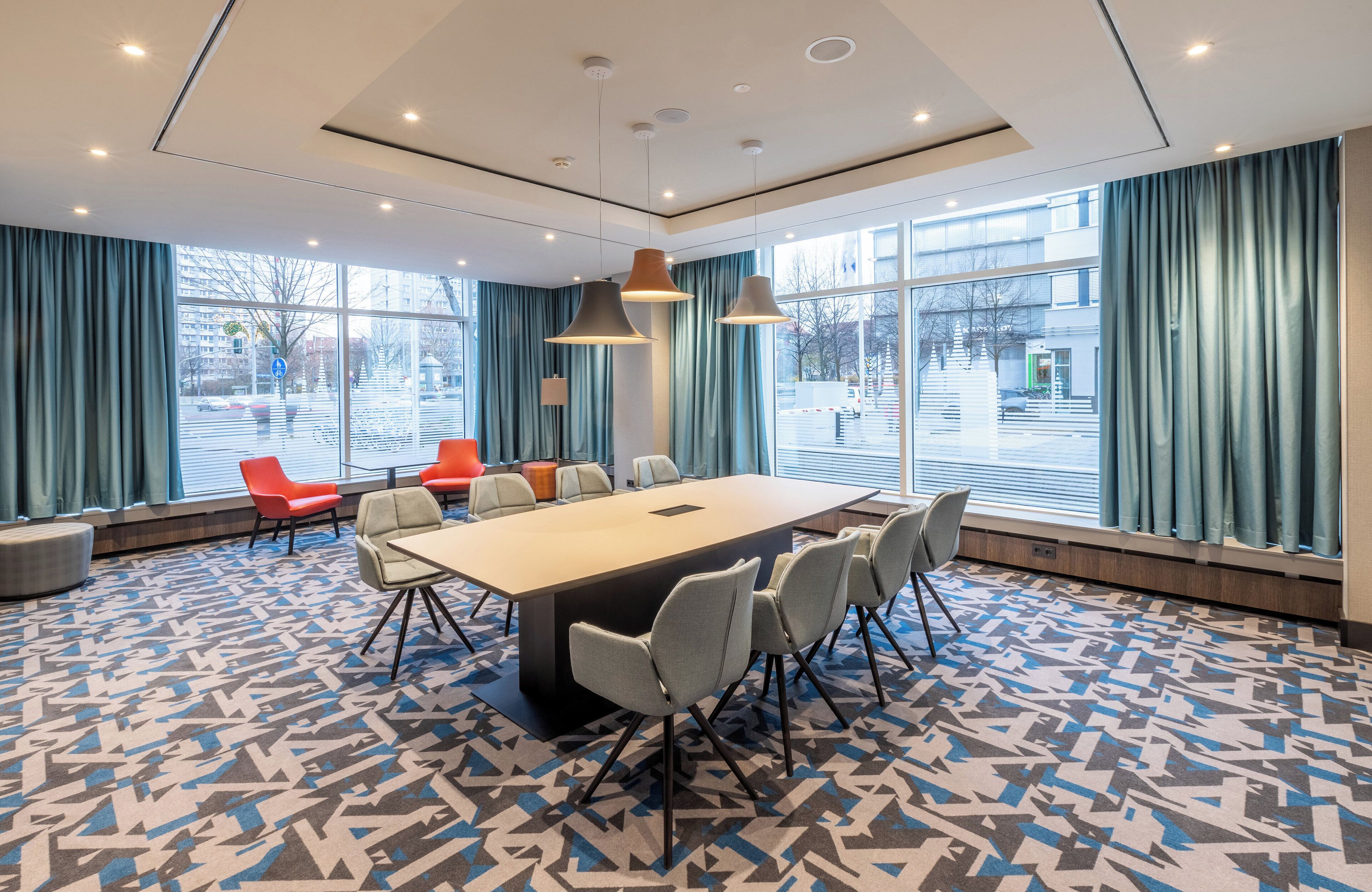 A conference room with a large table, chairs, and a patterned carpet.