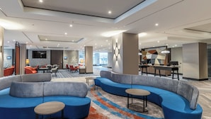 Eine moderne Hotelhalle mit einer gebogenen blauen Couch, einem Essbereich und einer Bar.