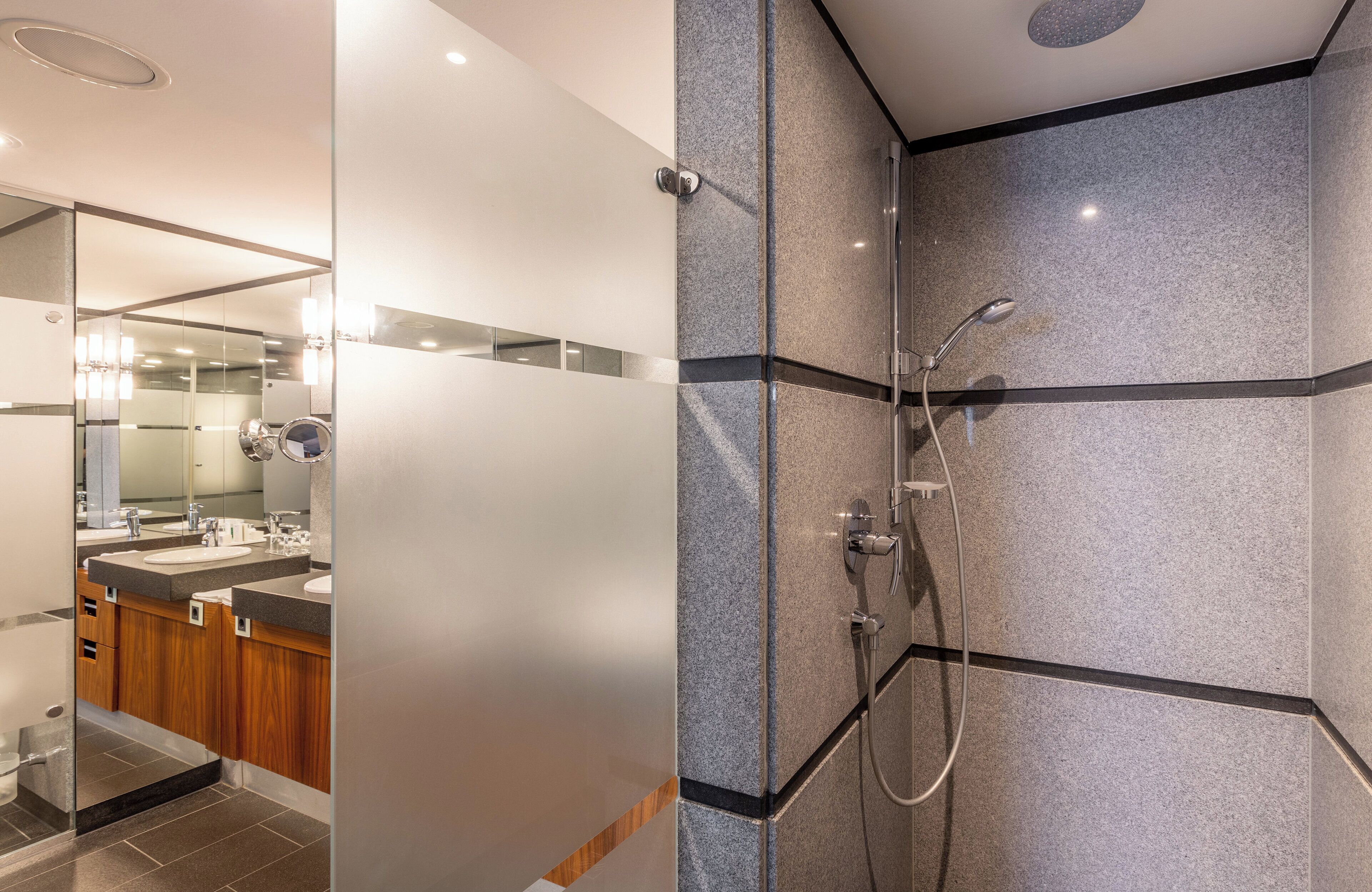 A modern bathroom with a glass shower enclosure, a vanity with a mirror, and a sink.