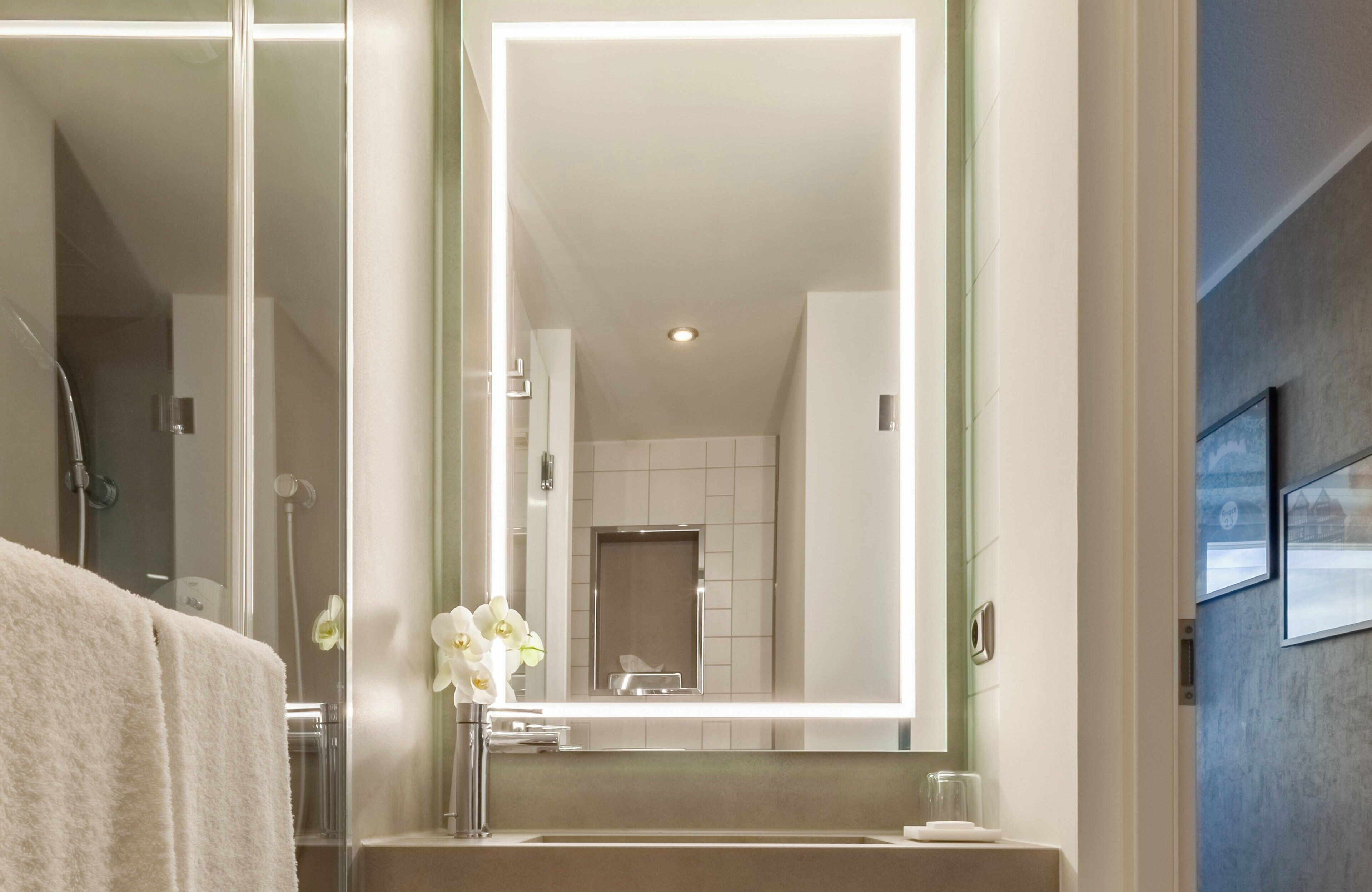 Un baño moderno con un espejo grande, un lavabo y una ducha.