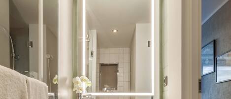 Un baño moderno con un espejo grande, un lavabo y una ducha.