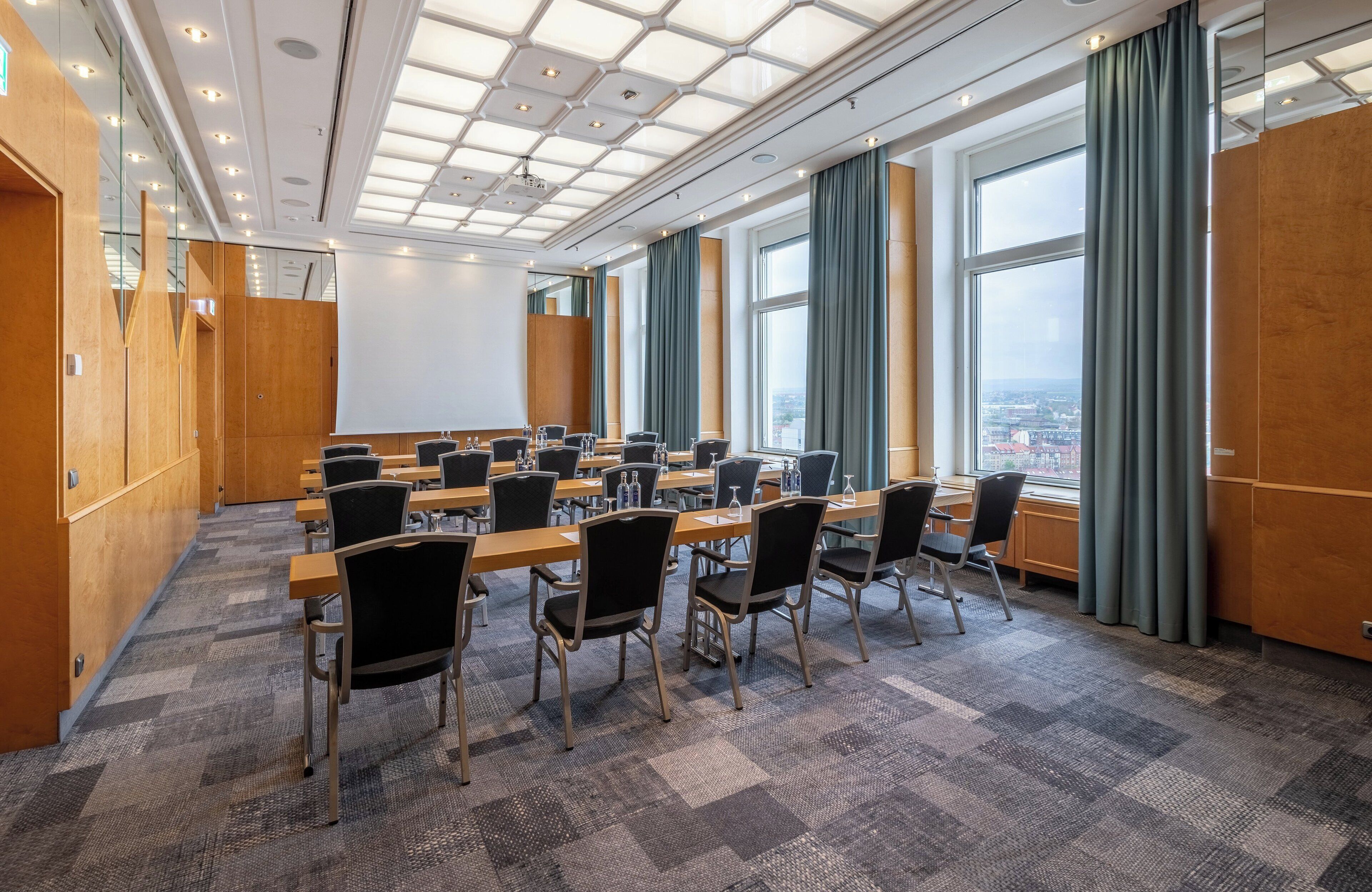 Een vergaderruimte met een lange tafel, stoelen en een stadszicht door grote ramen.