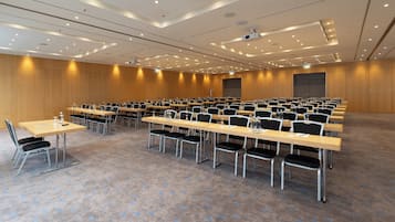 Ein Konferenzraum mit Tischen und Stühlen, ausgestattet mit Projektoren und einer großen Leinwand.