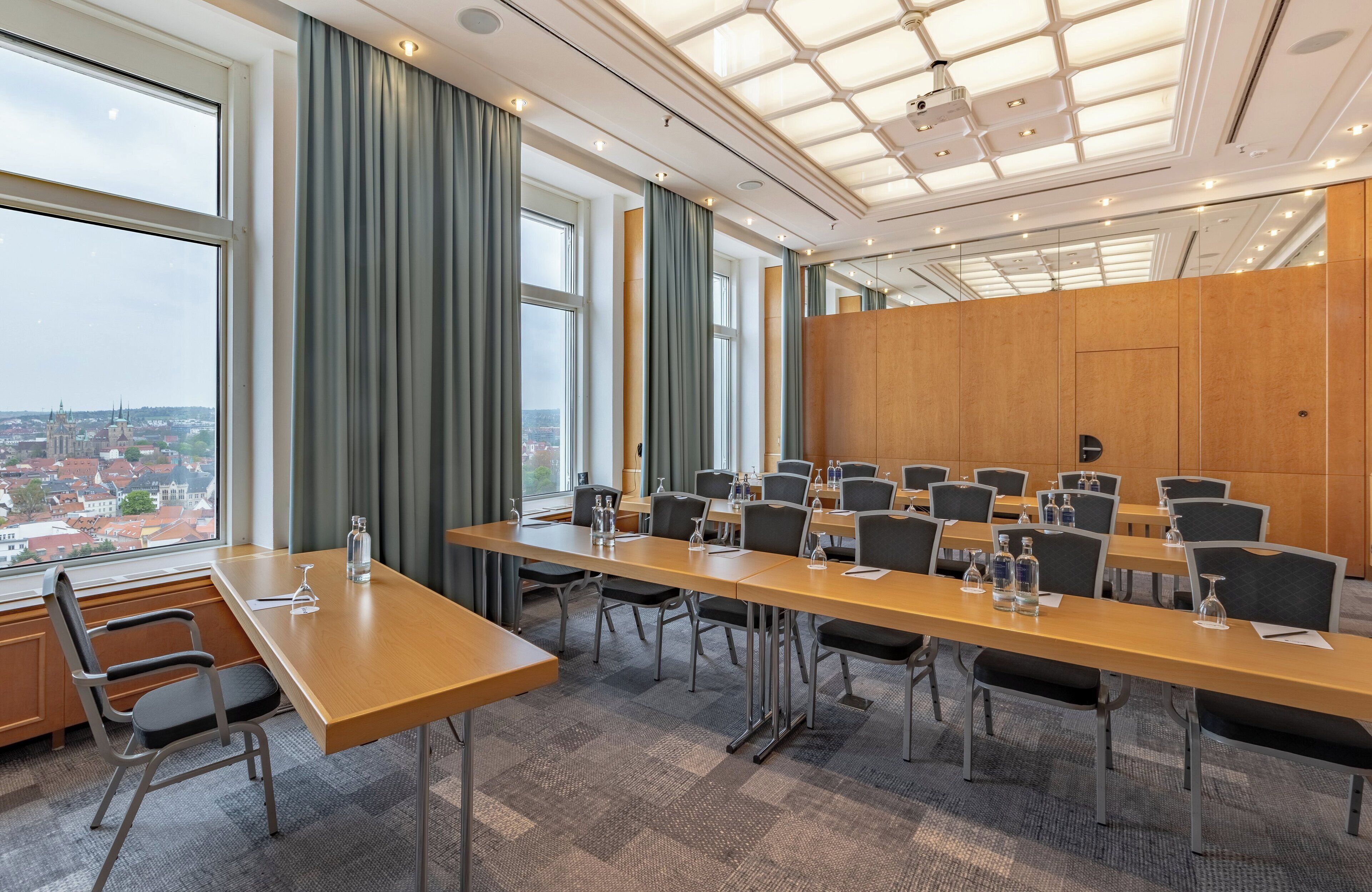 A conference room with a long table, chairs, and a city view through large windows.