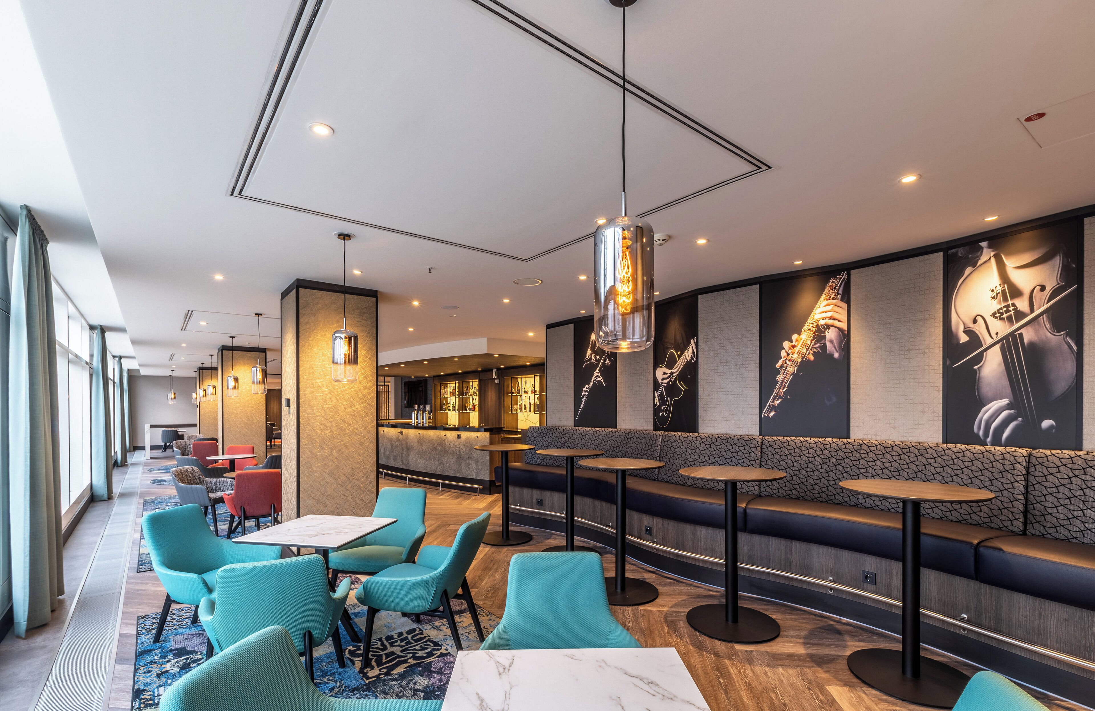 En modern restaurang med turkosa stolar, bord i marmor och en bardisk.