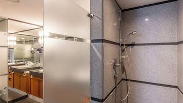 Un baño moderno con cabina de ducha de vidrio, tocador con espejo y encimera de granito.