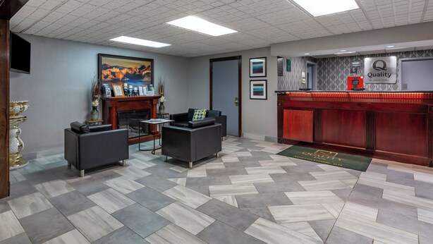 A lobby with a check-in counter, two sofas, a fireplace, and a painting on the wall. - Quality Inn Austintown - Youngstown West (Austintown)