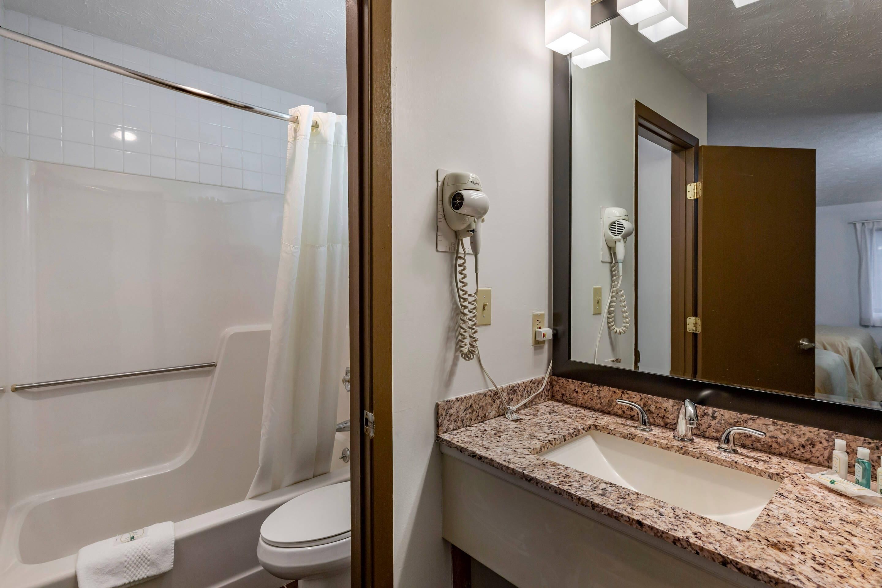 A bathroom with a shower, toilet, and a sink with a mirror.