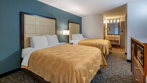 A hotel room with two beds, a dresser, a mirror, and a bathroom visible through an open door. - Quality Inn Austintown - Youngstown West (Austintown)