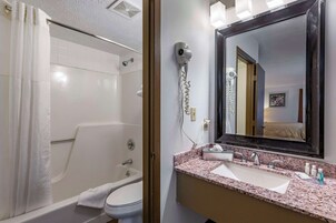 Un baño con ducha, inodoro, lavabo y un secador de pelo sujeto a la pared.