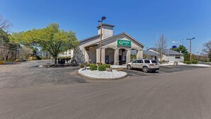 A Quality Inn by Choice Hotel with a parking lot and a white car parked in front. - Quality Inn Austintown - Youngstown West (Austintown)