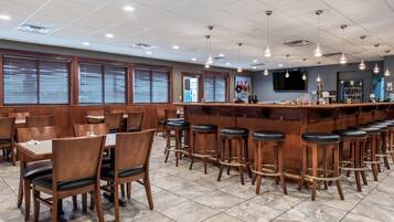 A restaurant interior with wooden tables and chairs, a bar area with stools, and a tiled floor.