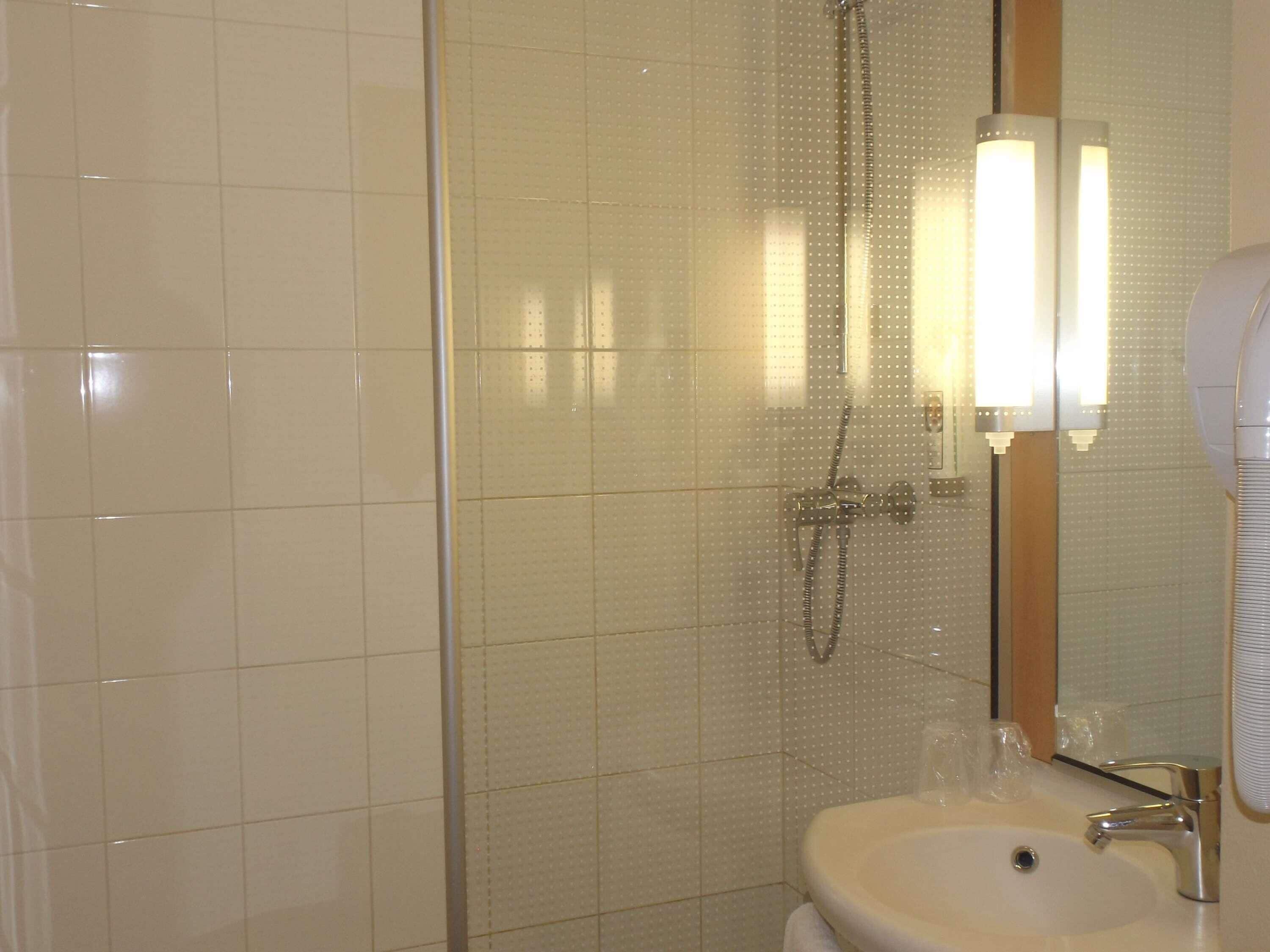 A bathroom with a shower, a sink, and a mirror.