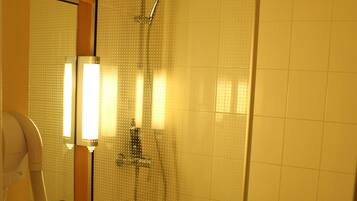 Un baño con ducha envuelta en vidrio, un lavabo y un espejo.
