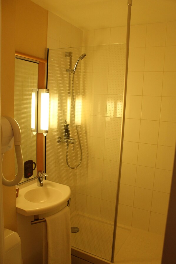 Un baño con ducha envuelta en vidrio, un lavabo y un espejo.