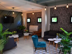 Un área de descanso moderna con sofás, mesas y plantas decorativas.