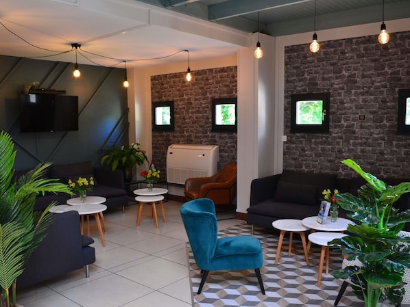 A modern lounge area with sofas, tables, and decorative plants. - Hôtel ibis Abbeville (Abbeville)