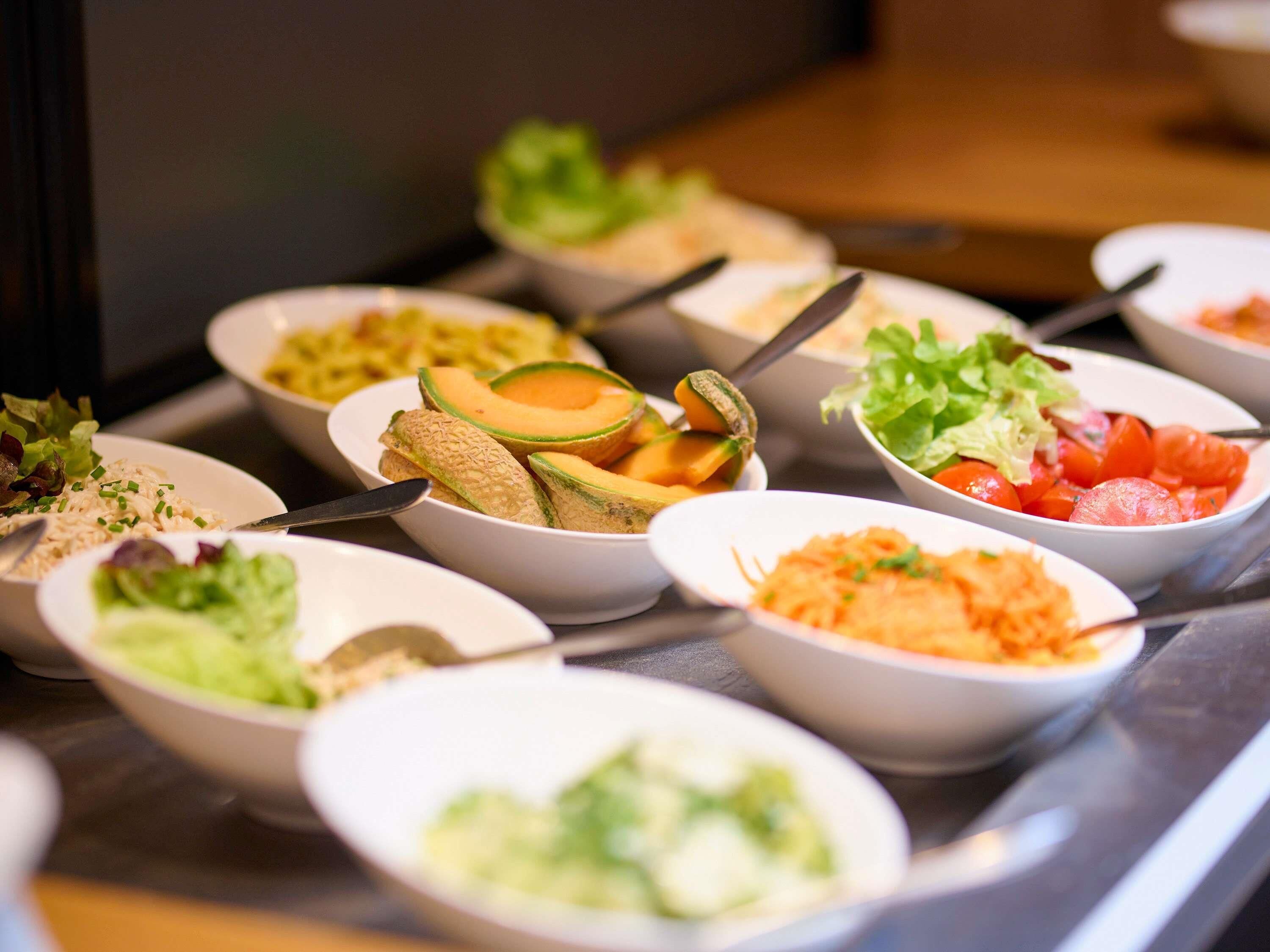 Un buffet proposant une variété de plats, notamment des salades, des fruits et des légumes.