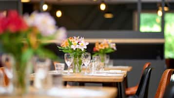 A restaurant setting with tables set for dining, featuring floral centerpieces and clear glassware.