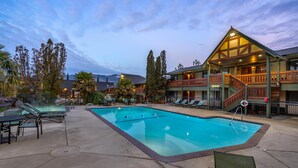 A pool area with lounge chairs and a hot tub, surrounded by a building with a balcony and stairs. - Best Western Windsor Inn (Ashland)